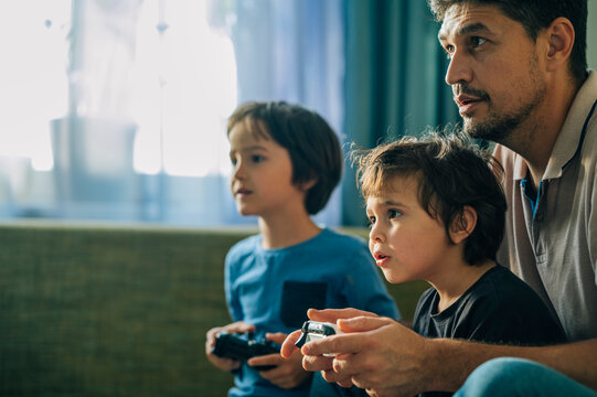 Father and children playing video game together at home