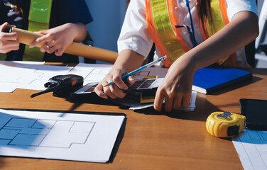 Closeup of team of industrial engineers meeting analyze machinery blueprints consult project on table in manufacturing factory. Working in manufacturing plant or production plant.