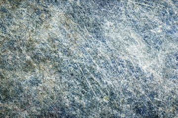 Scratched metal surface background closeup. Distressed steel texture with blue and rusty tones. Industrial grunge pattern with random lines and wear. Rough aged metal for design.