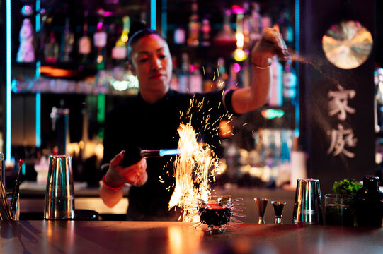 Bartender using torch to prepare flaming cocktail at bar