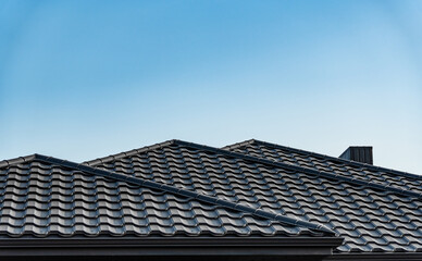 Several tiled rooftops of contemporary homes are visible against a bright blue sky, showcasing...