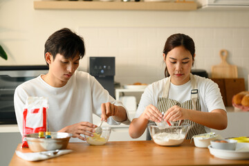 Young Asian Couple Preparing Cookie Dough at Home, Making Dough Together in a Home Kitchen