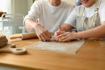 Close-up of a couple hands kneading cookie dough together, rolling and shaping with care and teamwork
