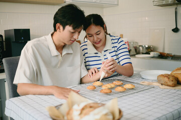 Happy duo decorating baked cookies on a wire rack with icing, perfect for home baking, food preparation, and family activities