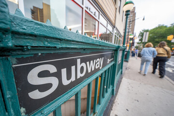 NYC subway entrance in Manhattan surrounded by buildings, street signs, and city atmosphere