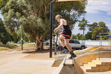 Teen boy riding scooter on ramps at skate park