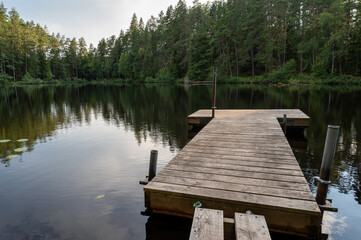 Calm forest lake with small jetty for fishing