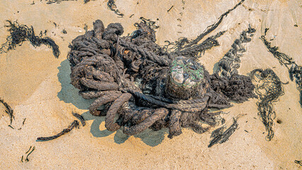 Oil pollution of sea, coast. Floating objects (flotsam, fragments of fishing nets) are covered with fuel oil and bring toxin to other parts of sea, secondary pollution. South China Sea