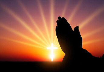 A silhouette of hands clasped in prayer against a vibrant sunset, with a radiant white cross and divine sun rays emerging from the horizon, symbolizing faith and hope.