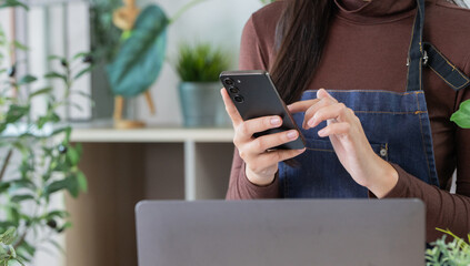 Digital Management. A woman using smartphone for plant business tasks.