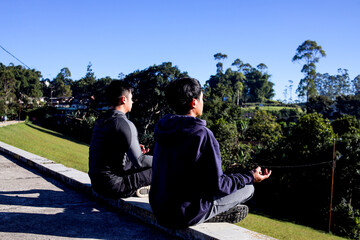 Two Men Meditating Outdoors in Yoga Pose, Eyes Closed