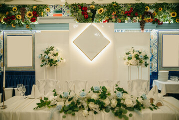 The presidium for the newlyweds in the banquet hall is prepared for the celebration, white tablecloths, a set table, white flowers