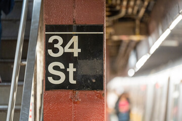 Interior view of 34th Street subway station sign in New York City with bustling platform