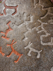 The background is a rock drawing of ancient people close up