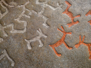 The background is a rock drawing of ancient people close up