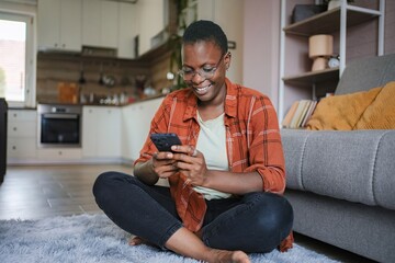 Smiling young woman using mobile phone at home