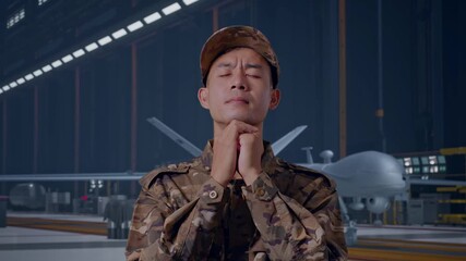 Close Up Of Asian Man Army Soldier Uniform Praying With Modern Military Drone In Maintenance Hangar - Powered by Adobe