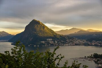 view over Lugano, Switzerland, at sunset, with Monte San Salvatore bathed in golden light