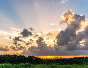 Majestic sunset with glowing sun rays piercing through fluffy clouds over lush green fields