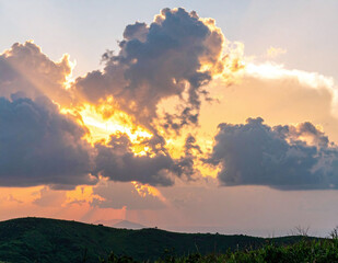 Golden sunset over green fields with radiant sunbeams highlighting the sky and clouds