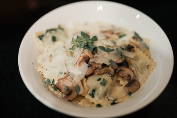 Tortellini pasta dish with creamy white sauce garnished with fresh oregano leaves