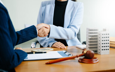 Business handshake in office with lawyer, cash, gavel, and building model. Concept of real estate...