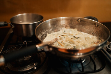 Tortellini pasta dish with creamy white sauce simmering in pan ready to serve