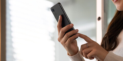 Close-up of young woman using smartphone with focus on hands and device
