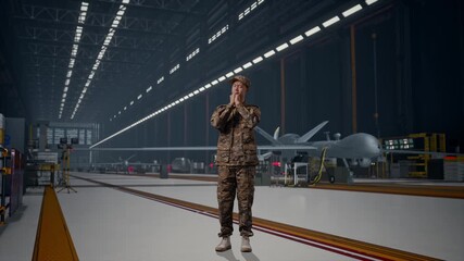 Full Body Of Asian Man Army Soldier Uniform Praying With Modern Military Drone In Maintenance Hangar - Powered by Adobe