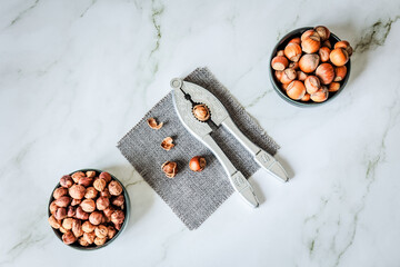Minimal Scandinavian scene — vintage nutcracker on grey cloth framed by bowls of raw and roasted...