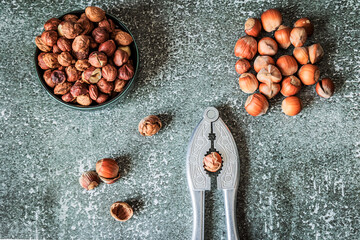 Top-view contrast shot: bowl of roasted hazelnuts, vintage nutcracker gripping a nut and pile of...