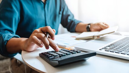Doing finance, budgeting and tax calculation. Close up woman hand using calculator to calculate home finance, accounting with laptop computer on table, budget management, monthly expenses.