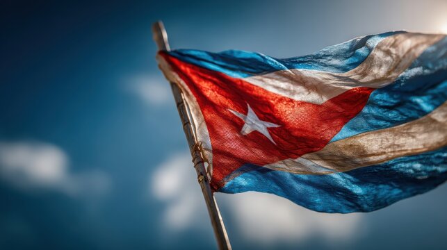 A vibrant Cuban flag waves against a bright blue sky, showcasing its iconic red, white, and blue colors, symbolizing national pride and identity.
