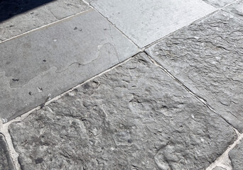 Old stone pavement with natural wear and texture in historic European city, close-up of weathered surface for background or design