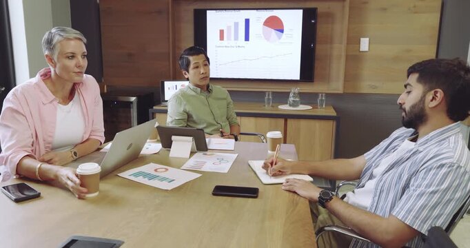 Diverse coworkers responding to charts at conference table jotting notes capturing data