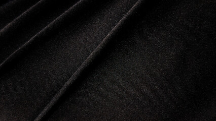 Obraz premium Macro shot of dark fabric texture, showing the intricate woven pattern of black material with subtle highlights and shadows. Detail and emphasizes the tactile quality of the textile.