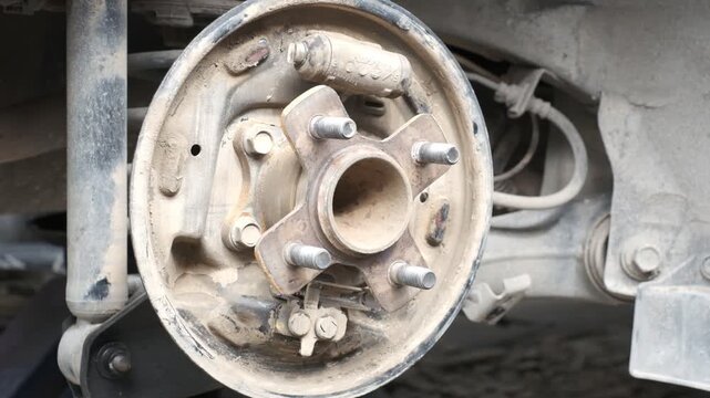 A dirty wheel with a few missing bolts. The wheel is on the back of a vehicle. Concept of neglect and disrepair