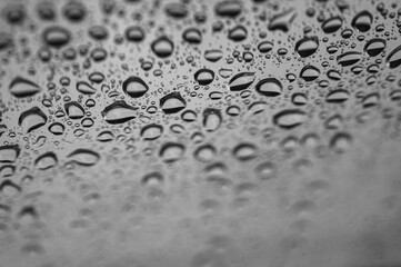 Close-up of raindrops on a window with selective focus. Black and white natural texture for a calm or melancholic mood