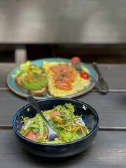 Two plates with avocado and red fish served on a wooden table, . Healthy breakfast outdoors with natural light.


