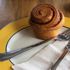 Fresh Cinnamon Roll on Plate with Fork and Knife