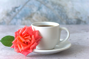 White cup of coffee or tea and salmon rose flower on a marbre background close up