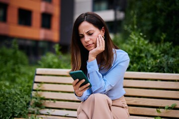 Woman Sitting on a Bench Distracted by Her Mobile Phone Outdoors
