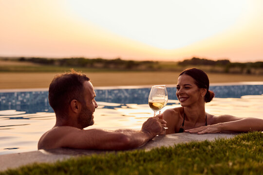 Couple Relaxing Together Enjoying Wine in a Poolside Sunset Setting