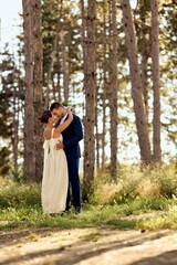 Fototapeta premium Romantic Wedding Couple Embracing in a Magical Forest Setting