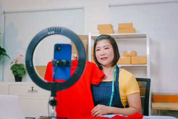 A young woman takes photos of clothes to sell online, holding a striped sweater and taking selfies...