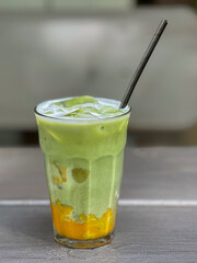 Glass of Matcha Mango Drink with Ice on Wooden Table

