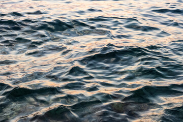 abstract background with gentle sea waves under sunset light. minimalist nature art. close up of calm sea water pattern in