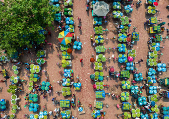 Kansat, Bangladesh - 15 June 2019: Aerial view of the vibrant Sona Masjid Road market, a tapestry of colorful umbrellas shading vendors displaying their wares.