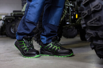 Industrial Worker in Blue Safety Shoes Standing by Off-Road Vehicles in Factory