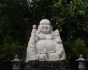 Joyful Laughing Buddha Statue Surrounded by Children in Temple Garden